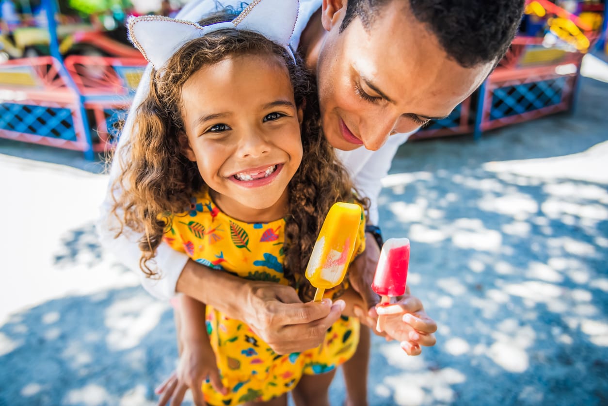Young father eat ice cream with his daughter at an amusement park