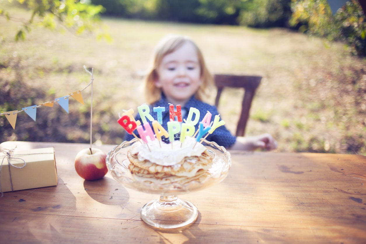 Cute little boy celebrating birthday with pancakes outside