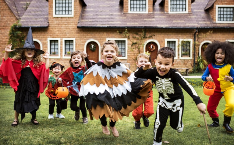 Little kids at a Halloween party running outside in their costumes